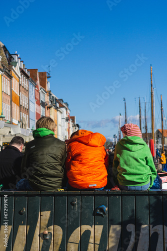 Three boys sitting on a ledge in a city