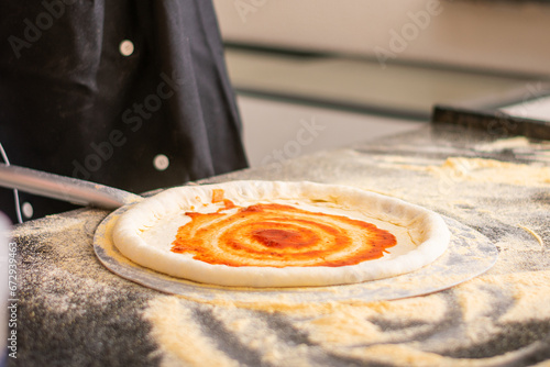 Pizza dough being prepared with cheese, tomato sauce, cheese