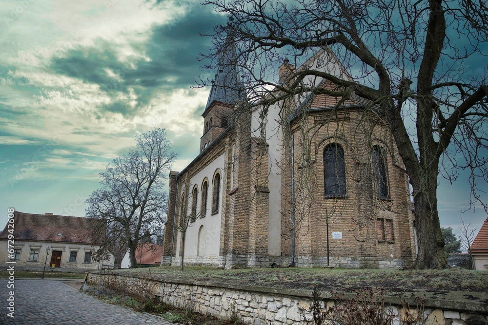 Old stone and brick church in a quaint residential neighborhood near a cobblestone path