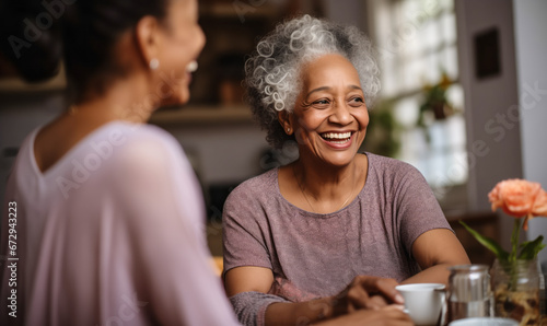 Two Ethnic Senior Friends Reconnect over Coffee in Kitchen