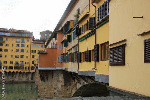 Old Bridge over water in Florence, Italy with urban buildings on the wall