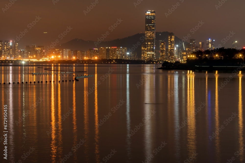 Scenic view of skyscrapers illuminated at night, reflecting on Shenzhen Bay, China