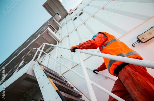 Construction worker wearing an orange vest is climbing a staircase photo