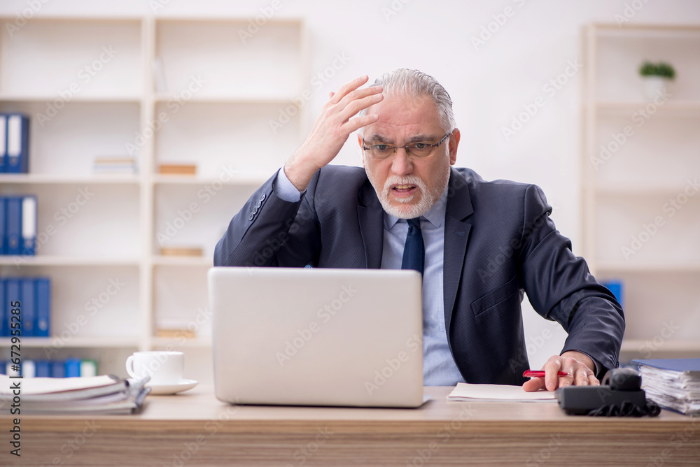 Old male employee working in the office Old male employee working in the office