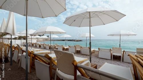 The famous beach Larvotto of principality of Monaco in sunny day, sun umbrellas, palm trees, azure water
