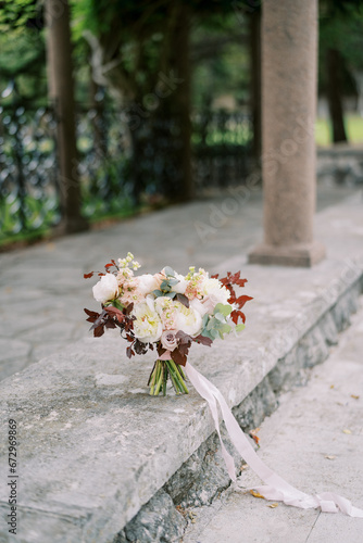 Wedding bouquet of flowers stands on a stone border near a column in the garden