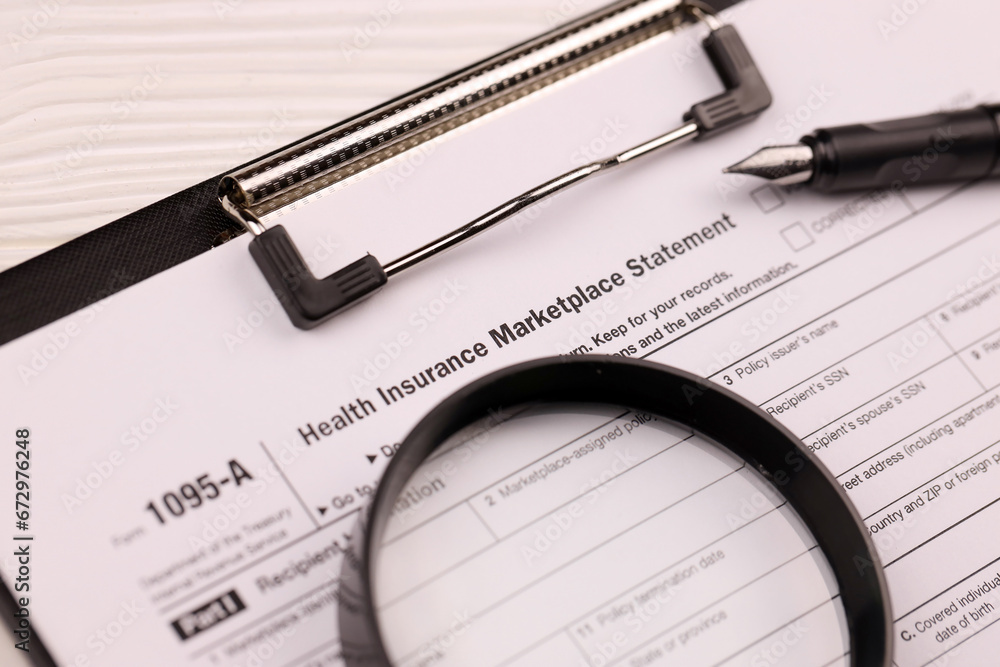 IRS Form 1095-A Health Insurance Marketplace Statement tax blank on A4 tablet lies on office table with pen and magnifying glass close up IRS Form 1095-A Health Insurance Marketplace Statement tax blank on A4 tablet lies on office table with pen and magnifying glass close up