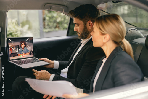 Cheerful business people have online meeting using laptop while sitting in car back seats © Yaroslav Astakhov