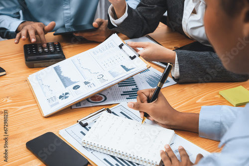 Multiracial analyst team use BI dashboard data to analyze financial report on meeting table. Group of diverse business people utilize data analysis by FIntech for business marketing decision. Concord