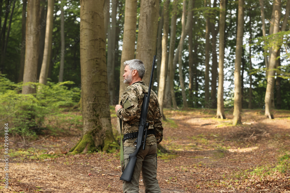 Man with hunting rifle wearing camouflage in forest