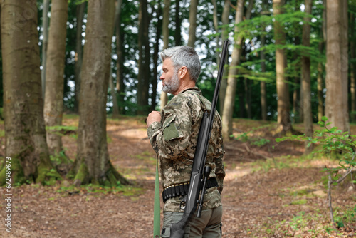 Man with hunting rifle wearing camouflage in forest