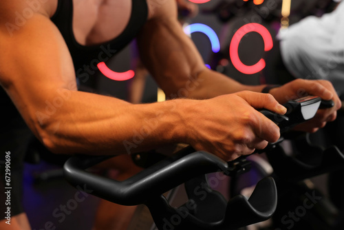 Man training on exercise bike in fitness club, closeup