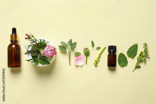 Bottles of essential oils, different herbs, rose flower and bud on beige background, flat lay
