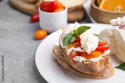Delicious sandwich with burrata cheese and tomatoes on grey table, closeup. Space for text