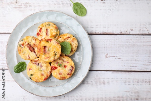 Delicious egg muffins with cheese and bacon on white wooden table, top view. Space for text