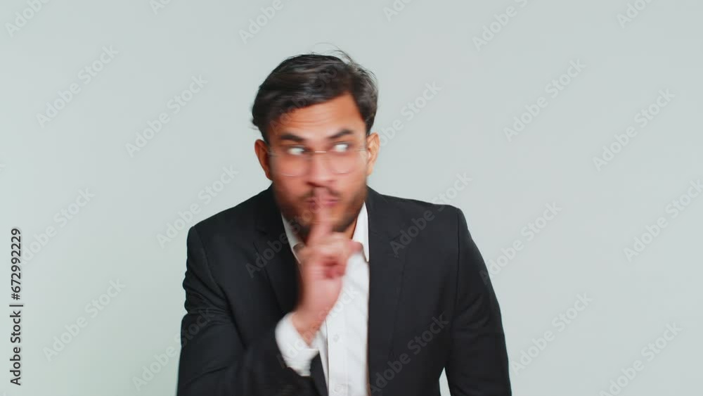 Shh be quiet please. Indian businessman presses index finger to lips makes silence gesture sign do not tells secret, stop talk gossip, confidential privacy. Arabian man guy isolated on gray background Shh be quiet please. Indian businessman presses index finger to lips makes silence gesture sign do not tells secret, stop talk gossip, confidential privacy. Arabian man guy isolated on gray background