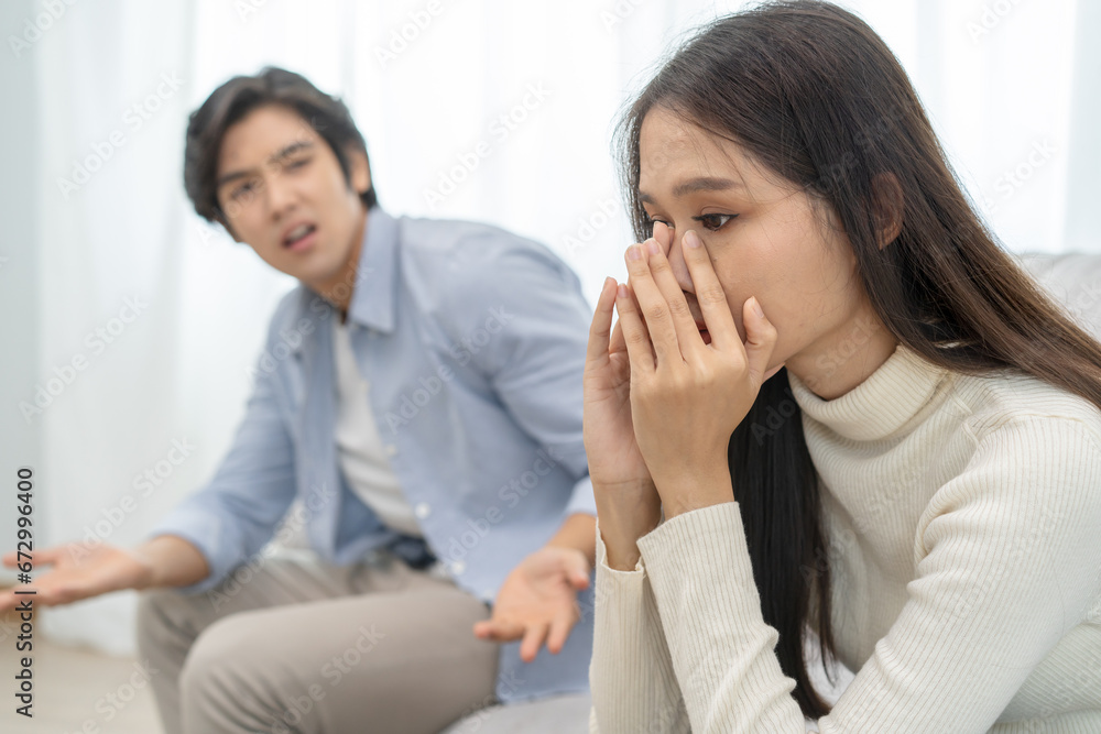 Family problems, Asian women cover her face and sit separately from husband feel disappointed after quarrels at home. Family problems, Asian women cover her face and sit separately from husband feel disappointed after quarrels at home.