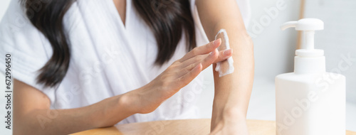 Young woman applying moisturizer cream to her arm in the morning routine. photo