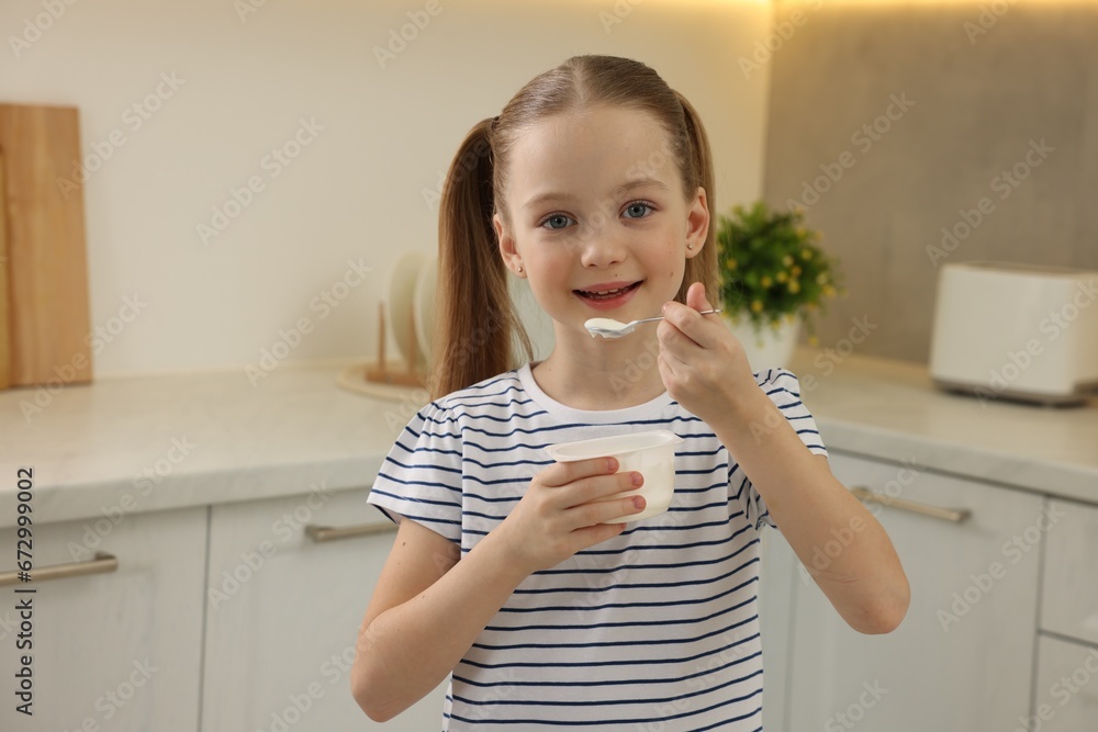 Cute little girl with tasty yogurt in kitchen Cute little girl with tasty yogurt in kitchen
