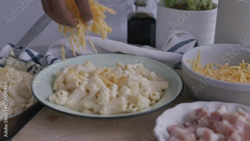 Grated pizza cheese mozzarella medium close up, woman chef hand touching cheese for Italian pasta or pizza. Macro close up of cheddar cheese adding pasta to the dish. Macaroni and Cheese dinner. photo