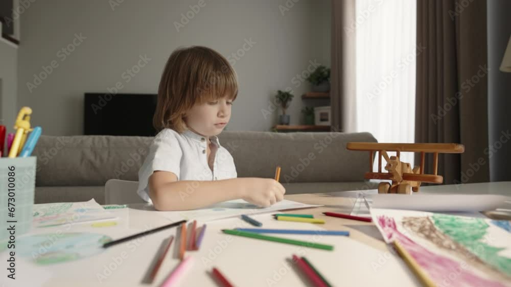 Concentrate little boy indulges in creative side, scribbling away with colorful pencils at home. Artistic aspirations, happy childhood, igniting imaginative spirit and fostering creative development Concentrate little boy indulges in creative side, scribbling away with colorful pencils at home. Artistic aspirations, happy childhood, igniting imaginative spirit and fostering creative development