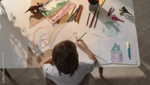 Top view close-up, creative little boy child drawing his family on paper. Family idyll. The concept of happy childhood in happy family. Smart kid draws himself with mom and dad holding hands. Adoption