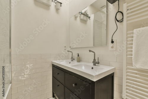 a bathroom with black cabinets and white tiles on the walls  along with a large mirror in the shower stall