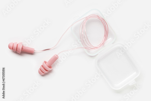 Reusable silicone earplugs pink color in box for swim, sleep, rest. Soft, flexible ear plug on string against noise, protect hear, close up object on white background, top view, flat lay