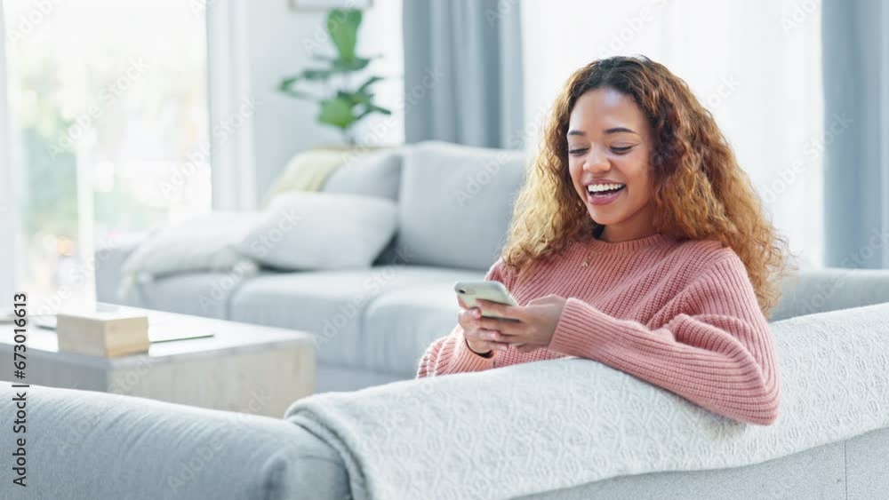 Happy woman laughing while texting on a phone and sitting on a sofa inside her living room with copy space. A cute young female enjoying online social media, looking comfortable and cheerful at home Happy woman laughing while texting on a phone and sitting on a sofa inside her living room with copy space. A cute young female enjoying online social media, looking comfortable and cheerful at home