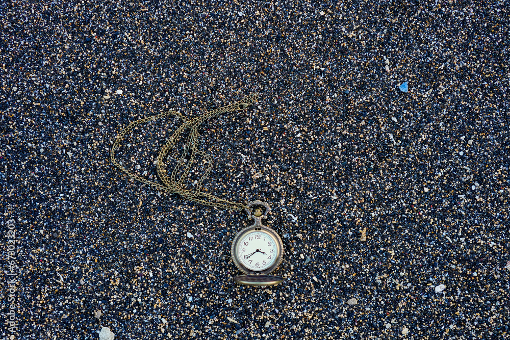 Gold color pocket watch lying on the sand. With copy space for text Gold color pocket watch lying on the sand. With copy space for text
