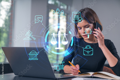 Pensive attractive beautiful businesswoman working on laptop, talking on phone at office workplace in background. Flying legal icons. Concept of law and order.