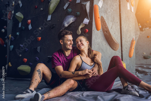 A strong couple of climbers against an artificial wall with colorful grips and ropes.