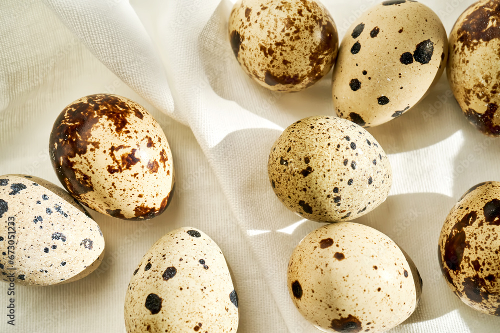 Obraz premium Quail eggs on a white linen towel close-up.