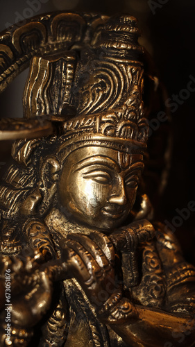 closeup of a shiny stone sculpture of hindu god lord krishna playing his flute inside an ancient temple