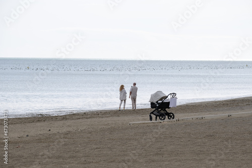 Playa de Málaga, pareja paseando por la playa con su recién nacido en brazos de la madre