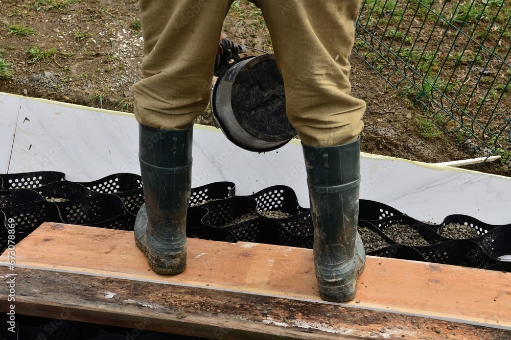Pouring crushed stone into the plastic net and compacting the plastic net with mesh