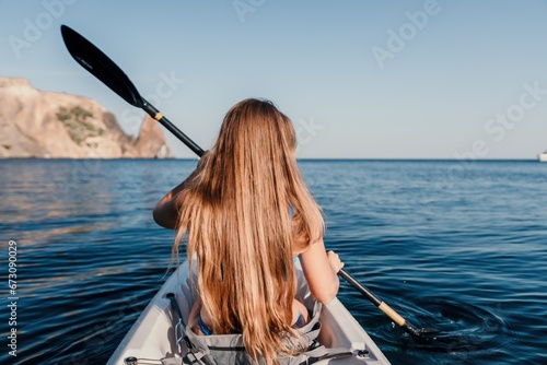 Woman in kayak back view. Happy young woman with long hair floating in kayak on calm sea. Summer holiday vacation and cheerful female people relaxing having fun on the boat.