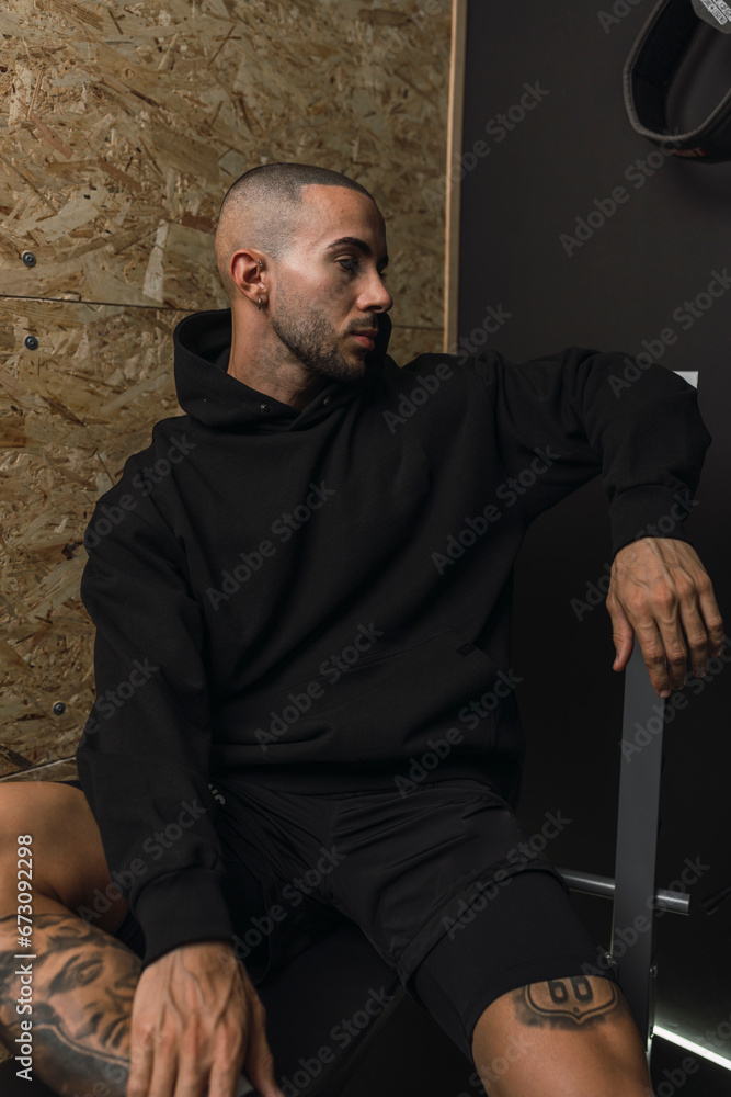 Obraz premium Chico joven musculado posando con ropa deportiva en gimnasio casero