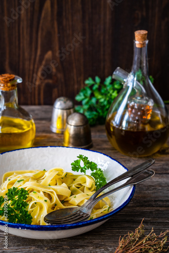 Tagliatelle aglio e olio with parmesan and garlic on wooden table 