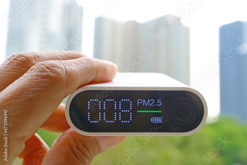Closeup of an air quality sensor in hand with group of high buildings in the backdrop photo
