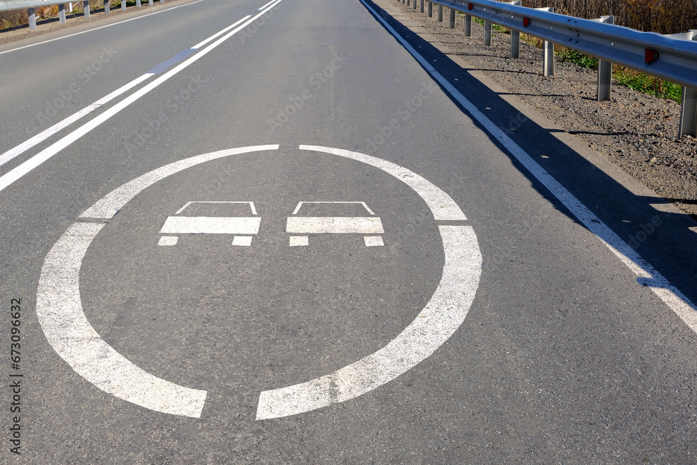 Obraz premium A road sign on the asphalt in front of the bridge prohibits overtaking.