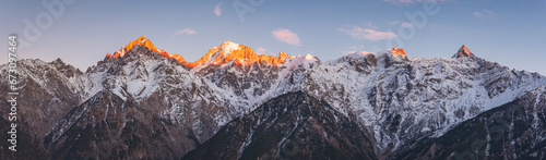Panoramic view during sunset over snow cladded Kinner kailash mountain peaks falls in Greater Himalayas mountain range from Kalpa village, Kinnaur, Himachal Pradesh, India.