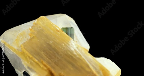 Elbaite verdelite (green tourmaline), on quartz and muscovite rotating in 4k isolated on black background. macro detail close-up rough raw unpolished semi-precious gemstone.  photo