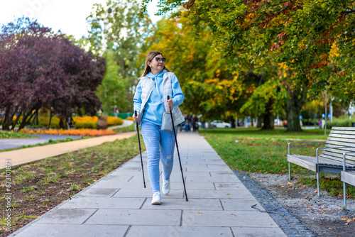 Nordic walking - mid-adult woman exercising in city park 
