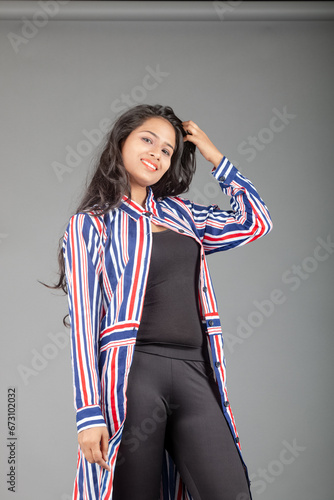 Beautiful woman wearing black leggings, black top and red, blue, white striped tunic. Female model in casual wear, advertisement shot.