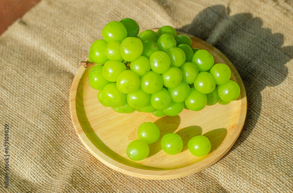 Bunches Shine Muscat grapes placed on wooden plate. Top view Bunches Shine Muscat grapes placed on wooden plate. Top view