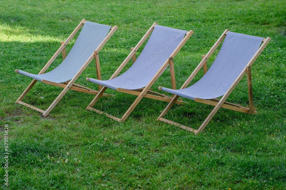 Stare drewniane leżaki plażowe na trawniku w ogrodzie  - obrazy, fototapety, plakaty 