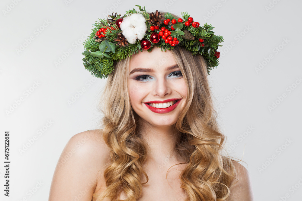 Naklejka premium Cheerful blonde woman portrait. Fashion female model with blond curly hairstyle, make-up and green and red winter accessories posing on white background