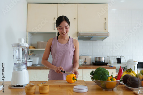 Beautiful young woman in exercise clothes is preparing vegetable salad in the kitchen. Food, vegetarian, diet, healthy. Prepare to cut vegetables, fruits, ingredients for cooking on the kitchen table