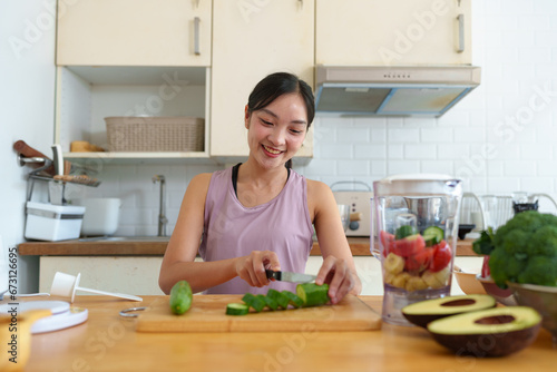 Confident young woman preparing vegetable salad in kitchen  healthy food vegetarian salad Healthy lifestyle cooking at home  preparing vegetables  fruits cut cucumber ingredients on the cooking table